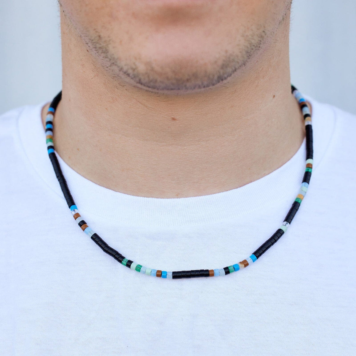A man wearing a beaded necklace with mixed seed beads