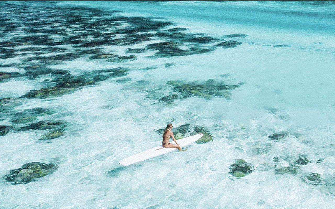 Surfer sitting on surfboard in clear ocean water